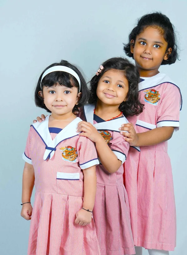 Three children smiling in Noah’s Ark Nursery uniforms